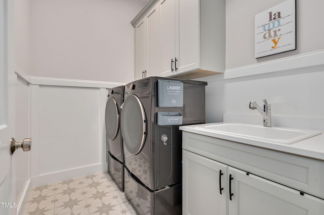 washroom featuring light floors, independent washer and dryer, a sink, and cabinet space