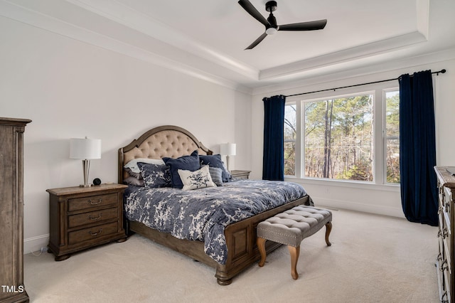 bedroom with light carpet, baseboards, a raised ceiling, and a ceiling fan