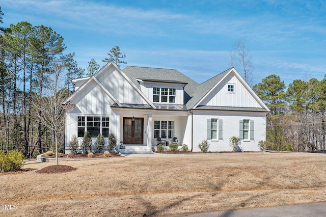 modern farmhouse style home with french doors, brick siding, board and batten siding, and a front lawn