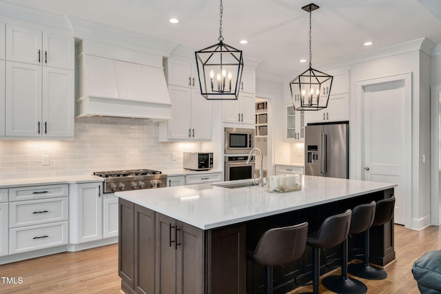 kitchen featuring appliances with stainless steel finishes, light countertops, premium range hood, and a sink