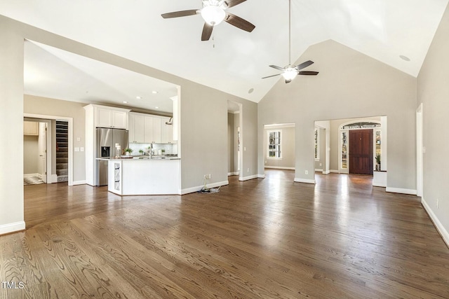 unfurnished living room with high vaulted ceiling, dark wood-type flooring, a sink, and baseboards