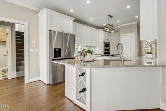 kitchen with white cabinets, ornamental molding, appliances with stainless steel finishes, light stone countertops, and pendant lighting