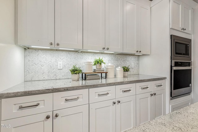 kitchen with light stone counters, appliances with stainless steel finishes, white cabinetry, and tasteful backsplash