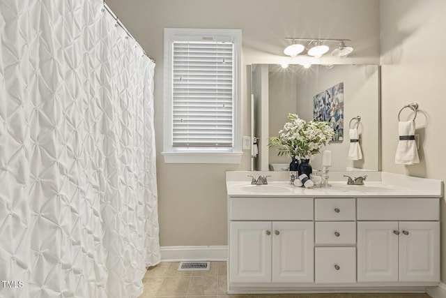 bathroom with tile patterned flooring, visible vents, a sink, and double vanity