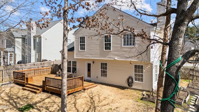 rear view of house featuring a chimney, a fenced backyard, and a wooden deck