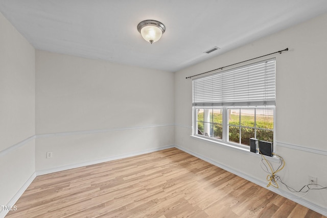 empty room featuring visible vents, baseboards, and wood finished floors