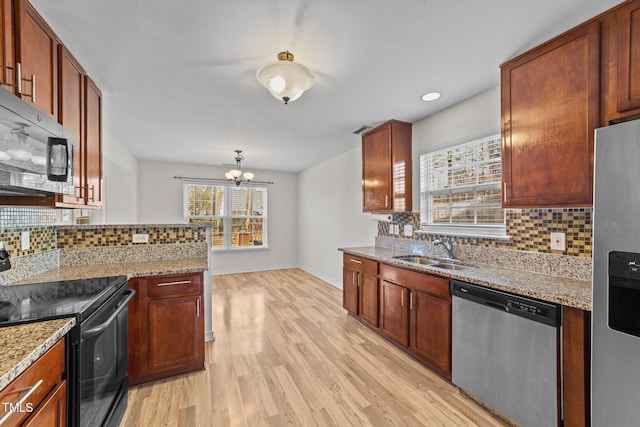 kitchen featuring light stone counters, light wood-style flooring, a sink, appliances with stainless steel finishes, and backsplash