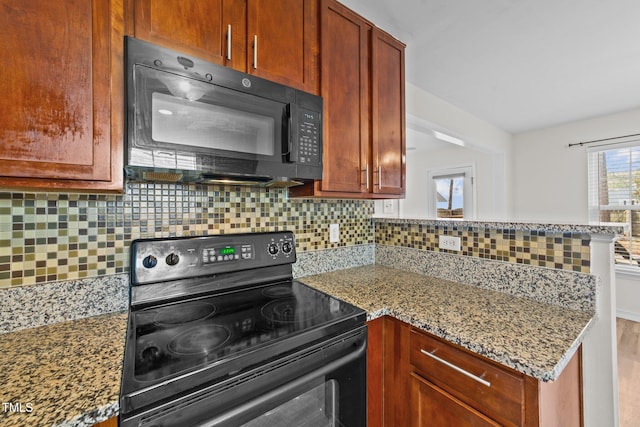 kitchen featuring a peninsula, black appliances, stone counters, and backsplash