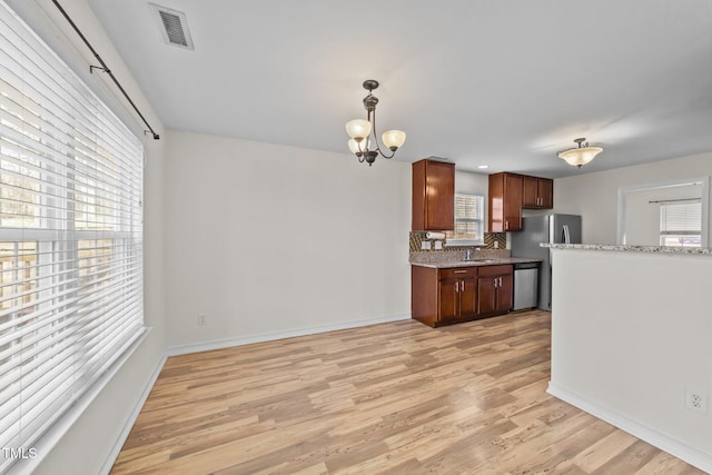 kitchen featuring visible vents, appliances with stainless steel finishes, light wood-style floors, a sink, and a chandelier