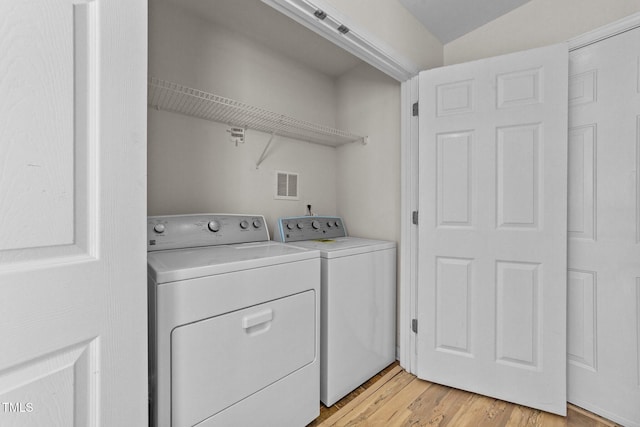 washroom featuring laundry area, light wood-type flooring, washing machine and clothes dryer, and visible vents