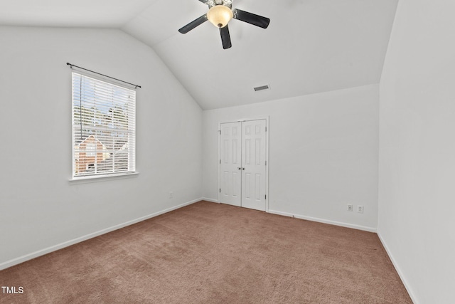 spare room with baseboards, visible vents, a ceiling fan, vaulted ceiling, and carpet flooring