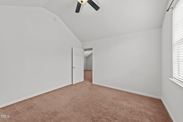 unfurnished bedroom featuring carpet, baseboards, vaulted ceiling, and a ceiling fan