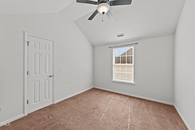 carpeted spare room featuring visible vents, vaulted ceiling, baseboards, and ceiling fan