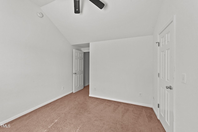 carpeted empty room with lofted ceiling, a ceiling fan, and baseboards