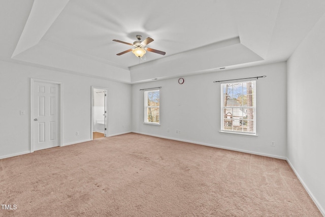 unfurnished bedroom with baseboards, a raised ceiling, carpet flooring, and ensuite bathroom