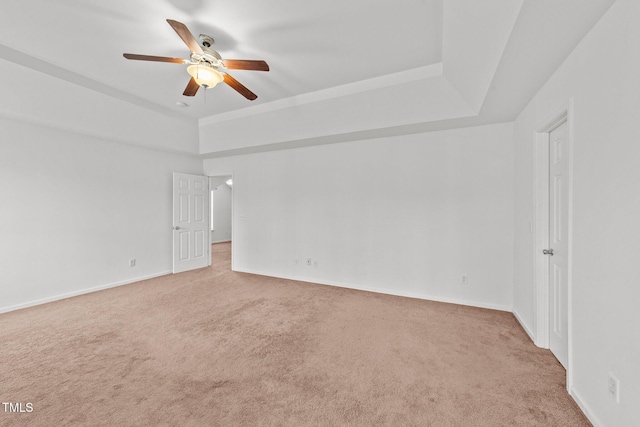 empty room featuring carpet floors, a raised ceiling, and a ceiling fan