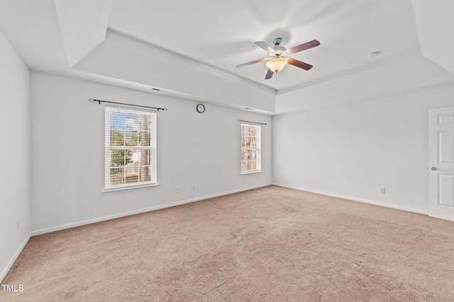 carpeted empty room with baseboards, a raised ceiling, and a ceiling fan