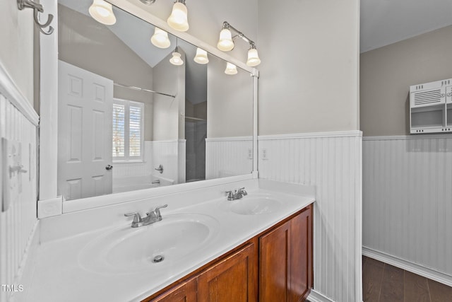 full bath with wood finished floors, a wainscoted wall, a sink, and double vanity