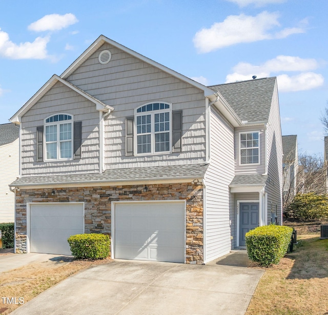 view of front of home featuring an attached garage, central air condition unit, concrete driveway, and roof with shingles