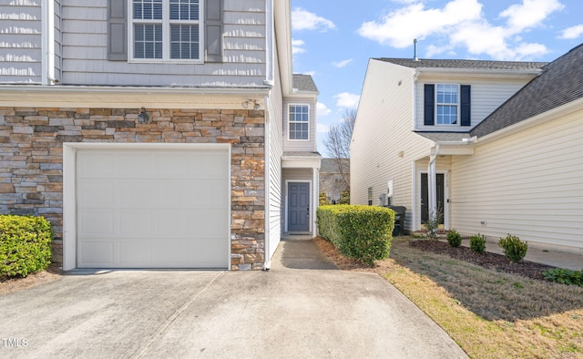 exterior space featuring a garage, stone siding, and concrete driveway