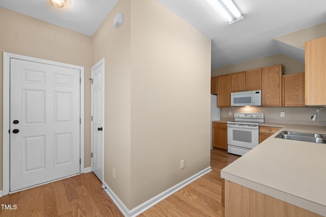 kitchen with white appliances, light wood finished floors, baseboards, light countertops, and a sink