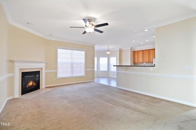 unfurnished living room with baseboards, ornamental molding, a tiled fireplace, and light colored carpet