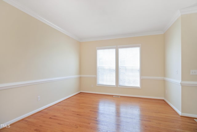 unfurnished room with light wood-style flooring, visible vents, baseboards, and ornamental molding