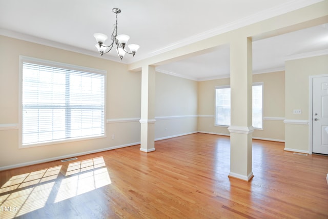 empty room with light wood-type flooring, decorative columns, baseboards, and crown molding