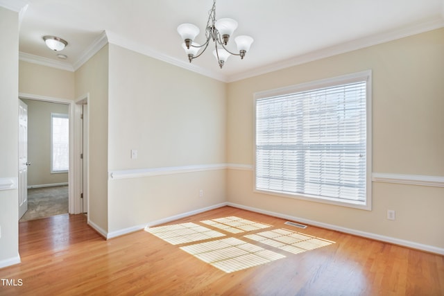 spare room featuring visible vents, an inviting chandelier, light wood-style floors, ornamental molding, and baseboards