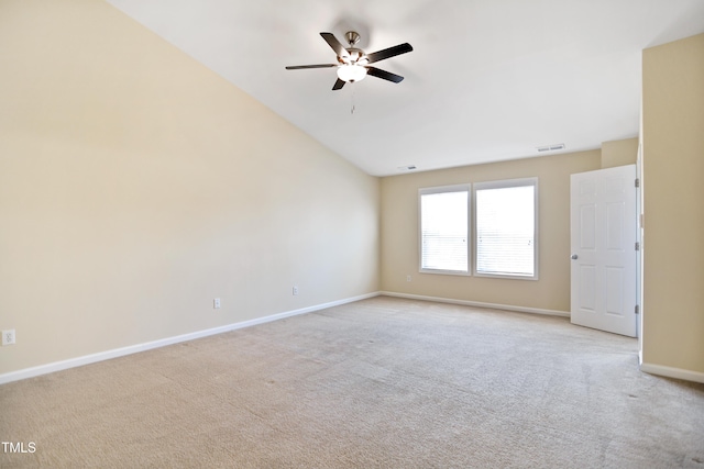 empty room featuring light colored carpet, visible vents, vaulted ceiling, ceiling fan, and baseboards