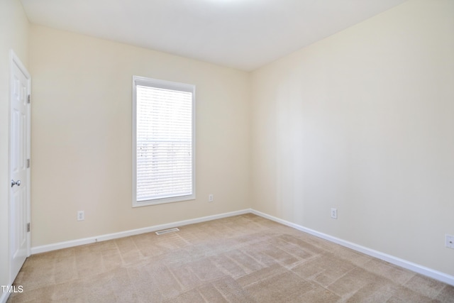 empty room featuring light carpet, visible vents, and baseboards