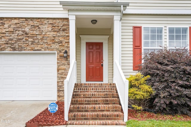 entrance to property featuring stone siding and a garage