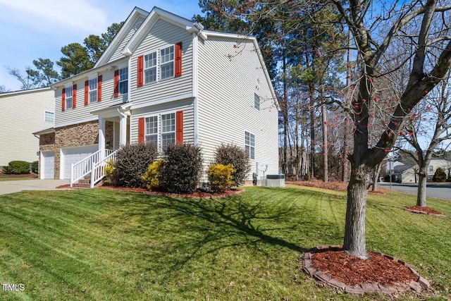 traditional-style house featuring an attached garage, concrete driveway, a front yard, and central air condition unit