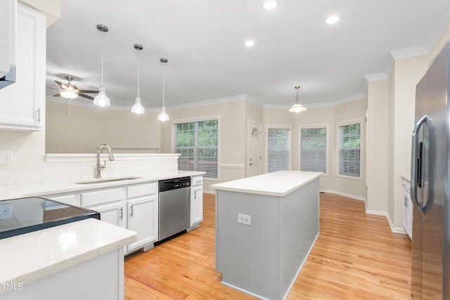 kitchen with stainless steel appliances, a sink, ornamental molding, light wood-style flooring, and white cabinets