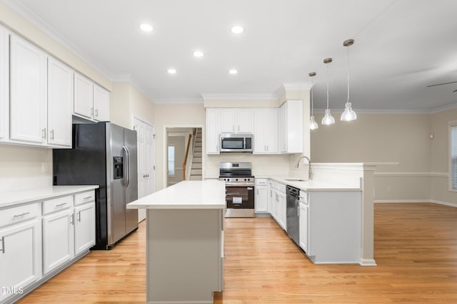 kitchen with appliances with stainless steel finishes, a peninsula, crown molding, a center island, and light wood-type flooring