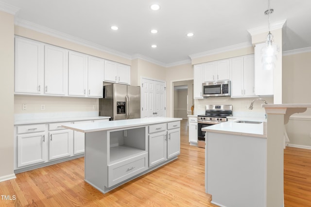 kitchen featuring appliances with stainless steel finishes, a sink, light countertops, light wood-type flooring, and ornamental molding