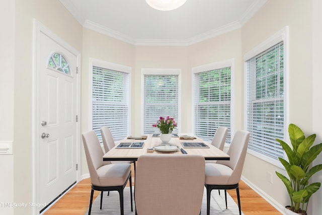 dining space featuring light wood-style flooring, crown molding, and baseboards