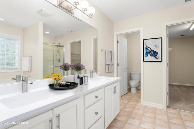 bathroom with a shower stall, toilet, a spacious closet, double vanity, and baseboards
