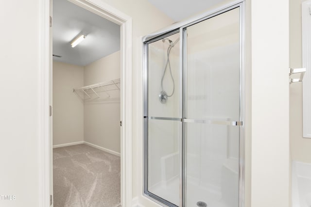 bathroom with a stall shower, a spacious closet, and baseboards