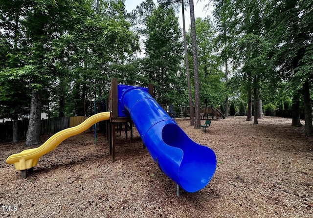 community playground with fence and view of scattered trees