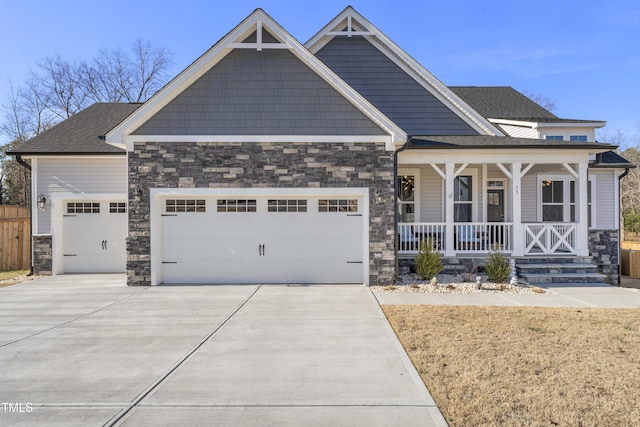 craftsman-style house with covered porch, concrete driveway, stone siding, and a garage