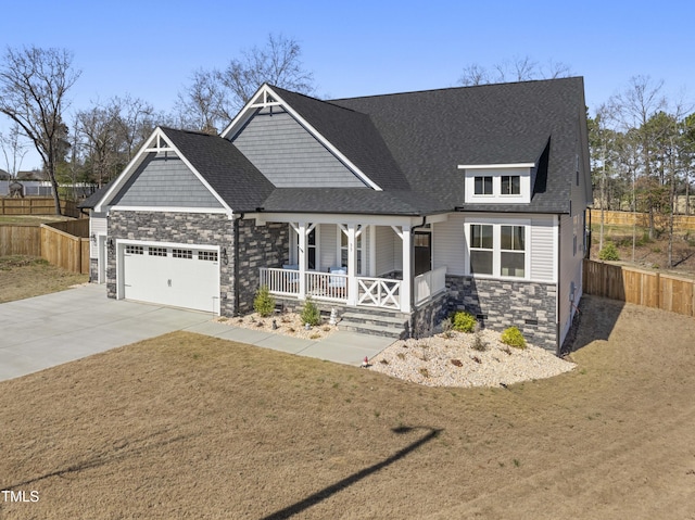 craftsman house featuring driveway, stone siding, an attached garage, covered porch, and fence