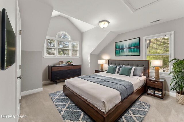 bedroom featuring multiple windows, visible vents, light colored carpet, and vaulted ceiling