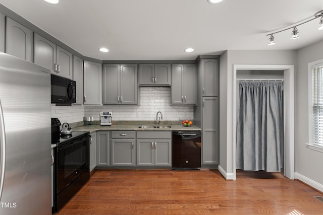 kitchen with a sink, decorative backsplash, black appliances, and gray cabinets