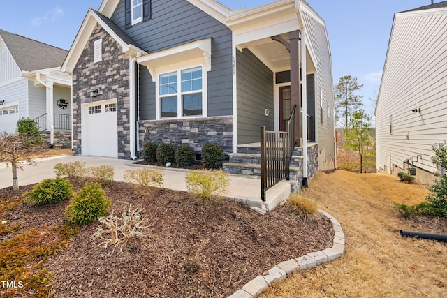 craftsman inspired home with a garage, stone siding, covered porch, and driveway