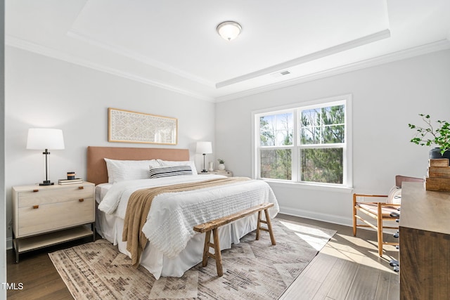 bedroom featuring a raised ceiling, visible vents, ornamental molding, wood finished floors, and baseboards