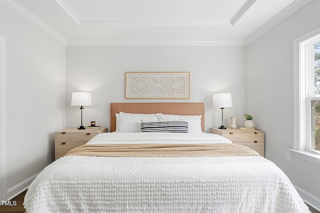 bedroom with baseboards, ornamental molding, a tray ceiling, and wood finished floors