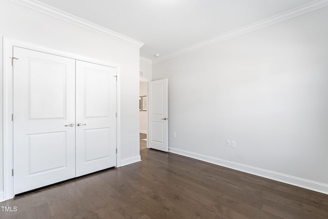 unfurnished bedroom featuring dark wood-type flooring, a closet, ornamental molding, and baseboards