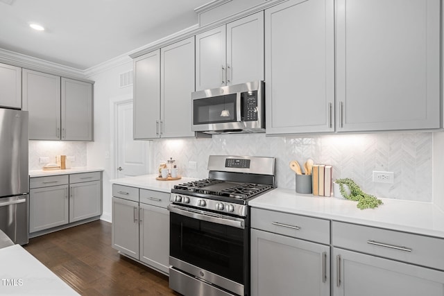 kitchen with appliances with stainless steel finishes, light countertops, dark wood-type flooring, and gray cabinetry