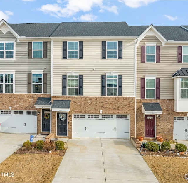 townhome / multi-family property featuring concrete driveway, an attached garage, brick siding, and roof with shingles